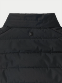 Close-up of a black puffer vest with a brand logo on a light gray background