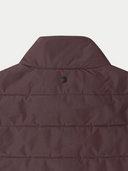 Close-up of a brown puffer vest with a brand logo on a light gray background