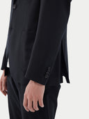 Men's Black single-breasted cashmere blazer worn by model, side view on white background